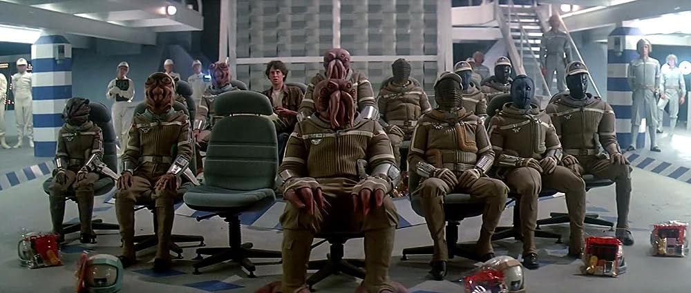 A young man and a group of alien pilots sit and look at camera from the 1984 film The Last Starfighter