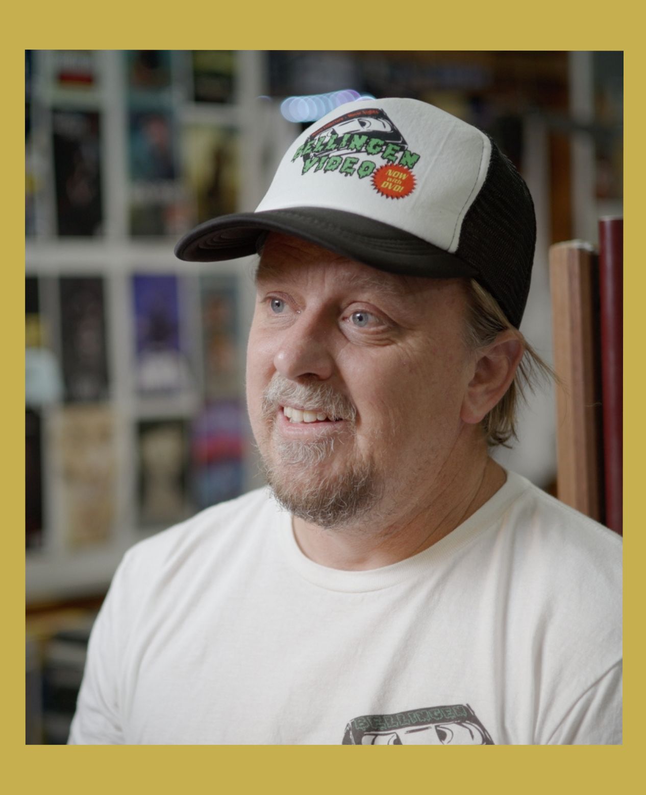 Image has a gold border and is of Rod O'Hara owner of Bellingen Video Connection in his store from the documentary Return Chute: The survival of a small town video store